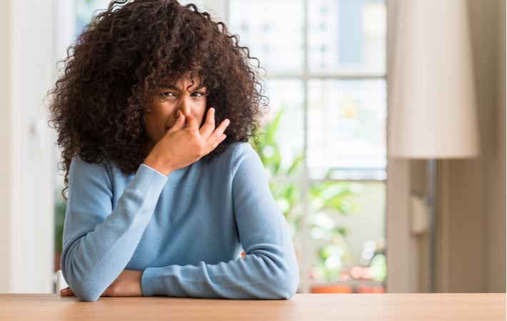 woman plugging her nose because of an unpleasant smell