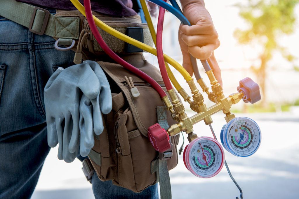 repair man with equipment used to check AC condenser