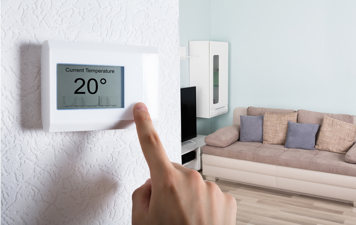 person adjusting a programmable thermostat