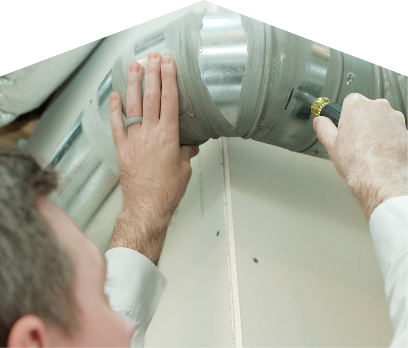 Furnasman HVAC technician inspecting and tightening a joint on a sealed metal air duct, performing maintenance work during an air duct cleaning task.