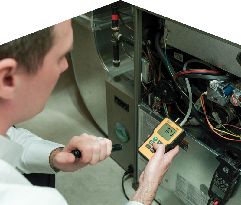 Furnasman HVAC specialist performing furnace repair on a heating system, using a digital manometer to check pressure. Furnasman HVAC specialist performing furnace repair on a heating sy