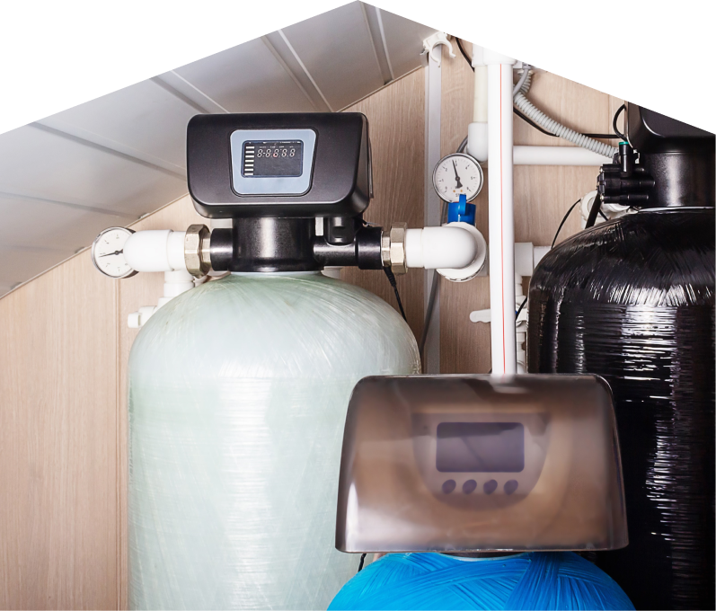 Furnasman home water filtration system featuring resin tanks, digital control heads, pressure gauges, and connected piping in a utility room. Furnasman home water filtration system featuring resin tanks, digital control heads, pressure gauges, and connected piping in a utility room.