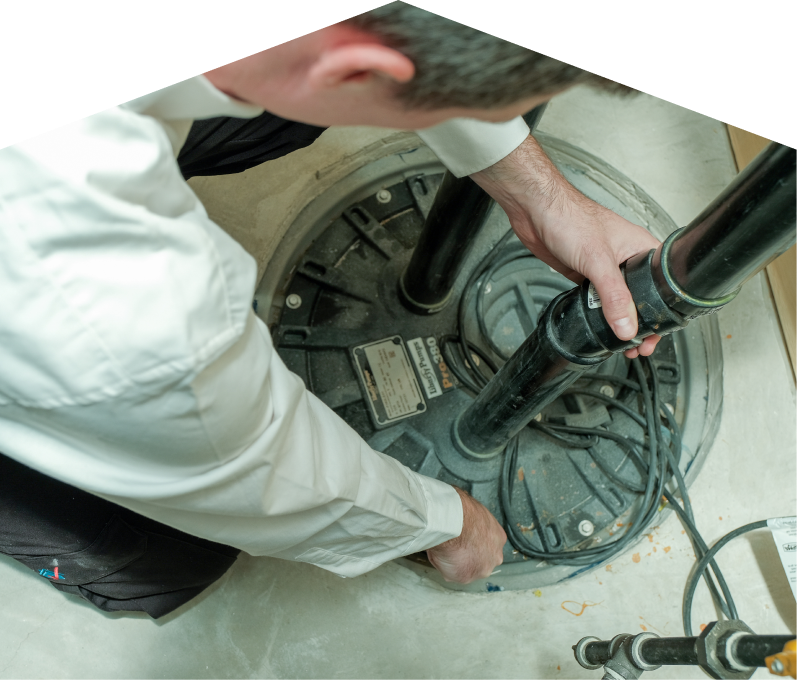 Furnasman sump pump specialist secures discharge piping on a sealed basin during a sump pump installation in a basement utility area. Furnasman sump pump specialist secures discharge piping on a sealed basin during a sump pump installation in a basement utility area.