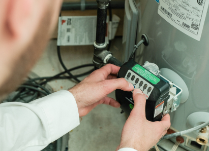 A Furnasman technician adjusts the control module on a residential water heater, verifying proper operating settings. A Furnasman technician adjusts the control module on a residential water heater, verifying proper operating settings.